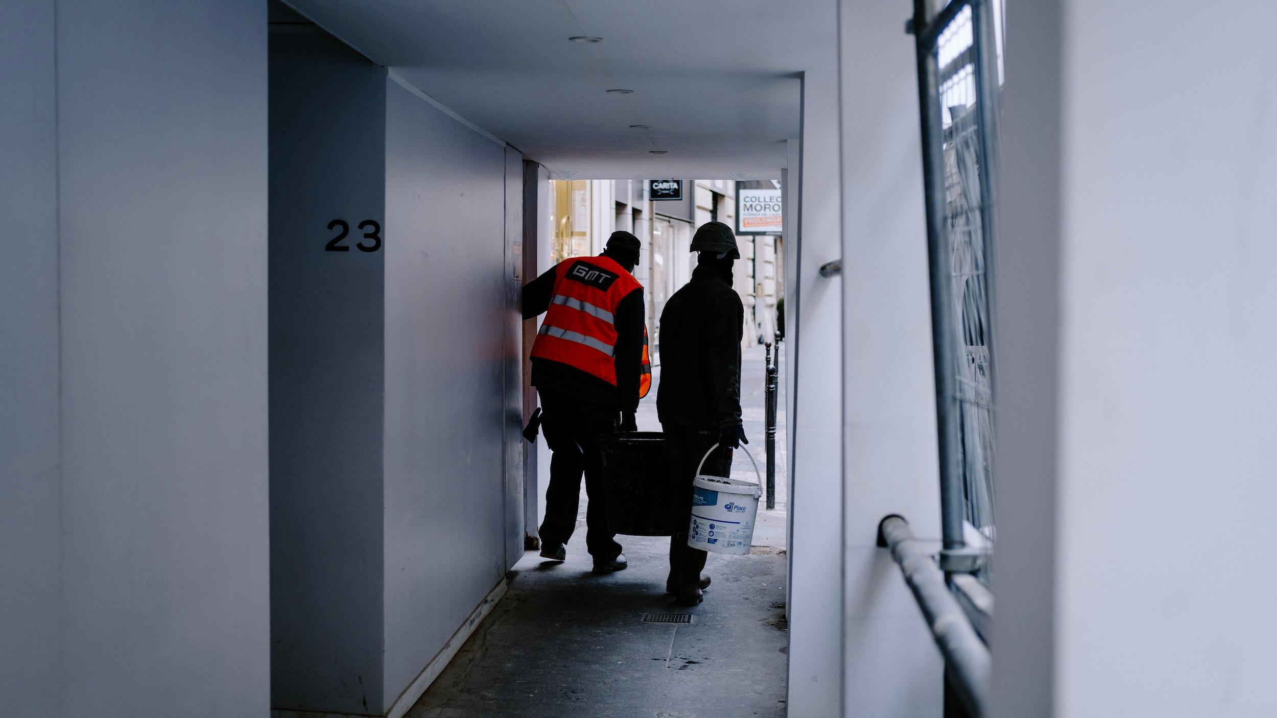 To bygarbejdere der bærer materialer i en bygang.